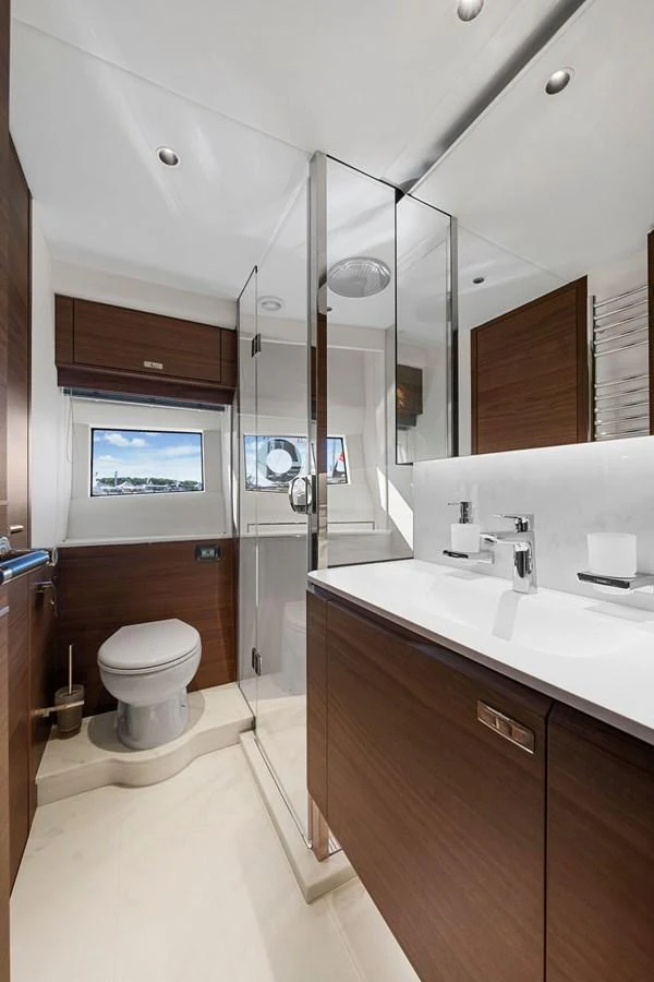 A sleek and modern yacht bathroom with wood accents and a glass-enclosed shower. aboard PRINCESS S72 Yacht for Sale