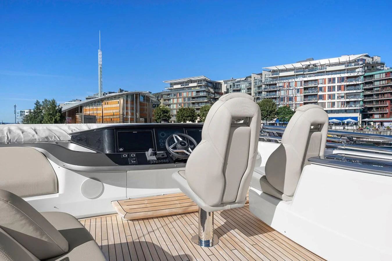 The yacht's helm area features modern controls and comfortable seating with a backdrop of a vibrant marina. aboard PRINCESS S72 Yacht for Sale