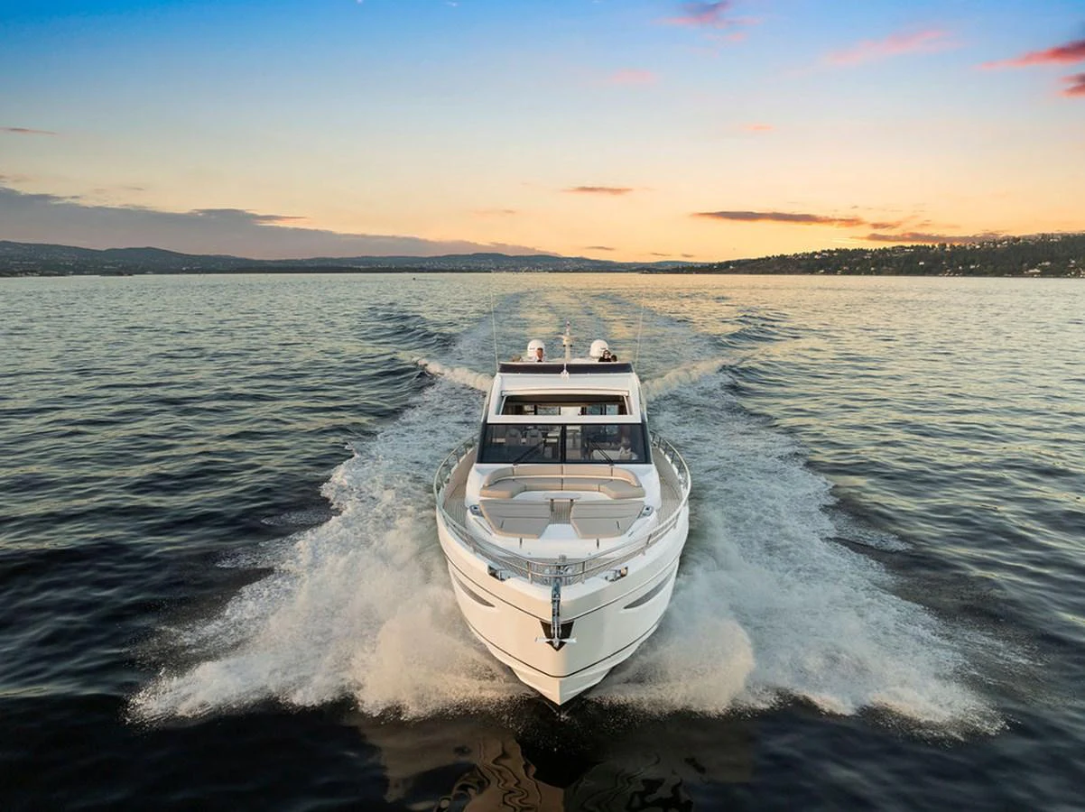 A sleek yacht cruises forward on calm waters at sunset, showcasing its modern design and powerful performance. aboard PRINCESS S72 Yacht for Sale