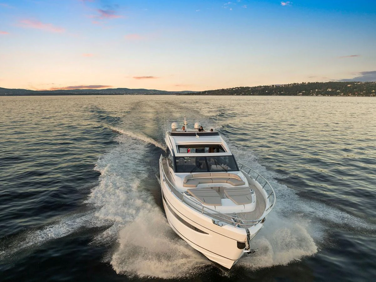 A sleek yacht cruises through calm waters at sunset, showcasing its modern design and powerful performance. aboard PRINCESS S72 Yacht for Sale