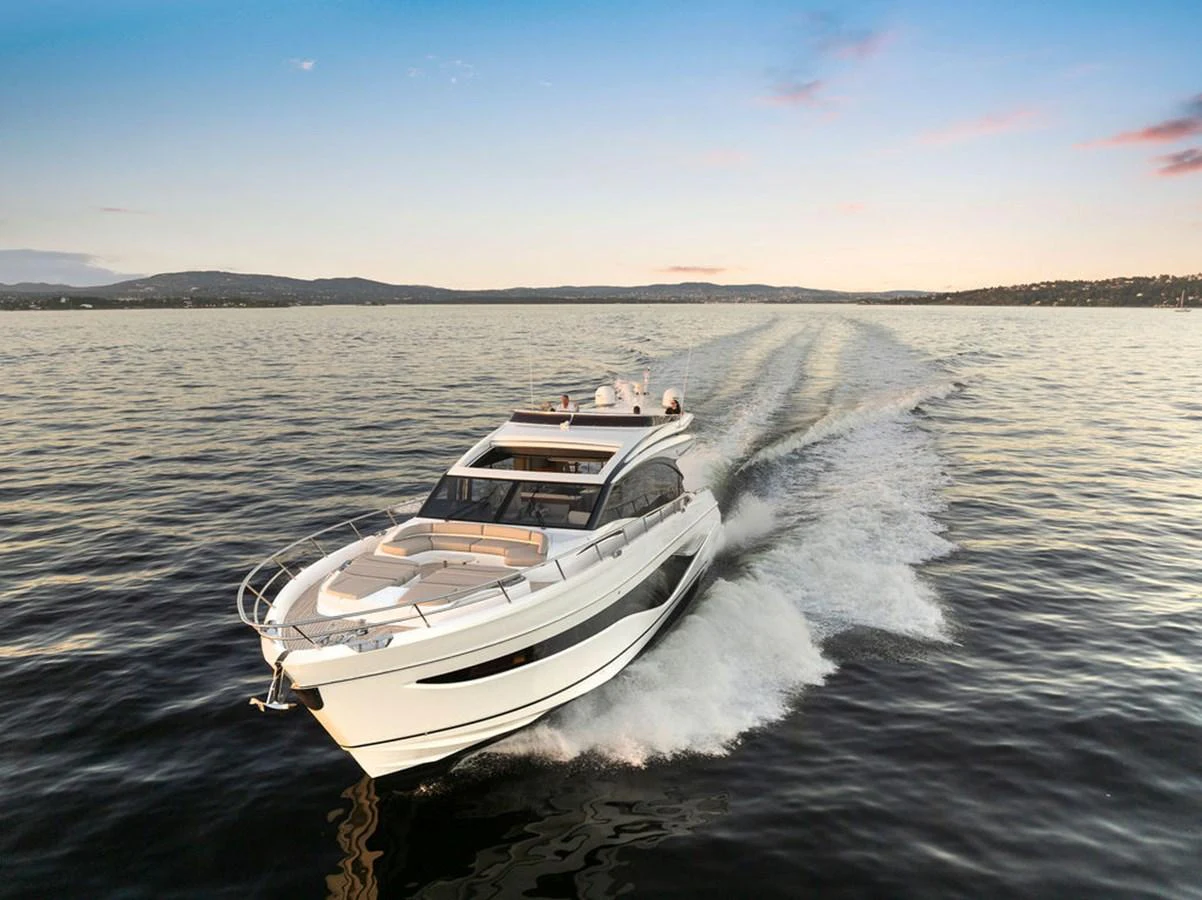 A sleek yacht cruises swiftly across calm waters at sunset. aboard PRINCESS S72 Yacht for Sale