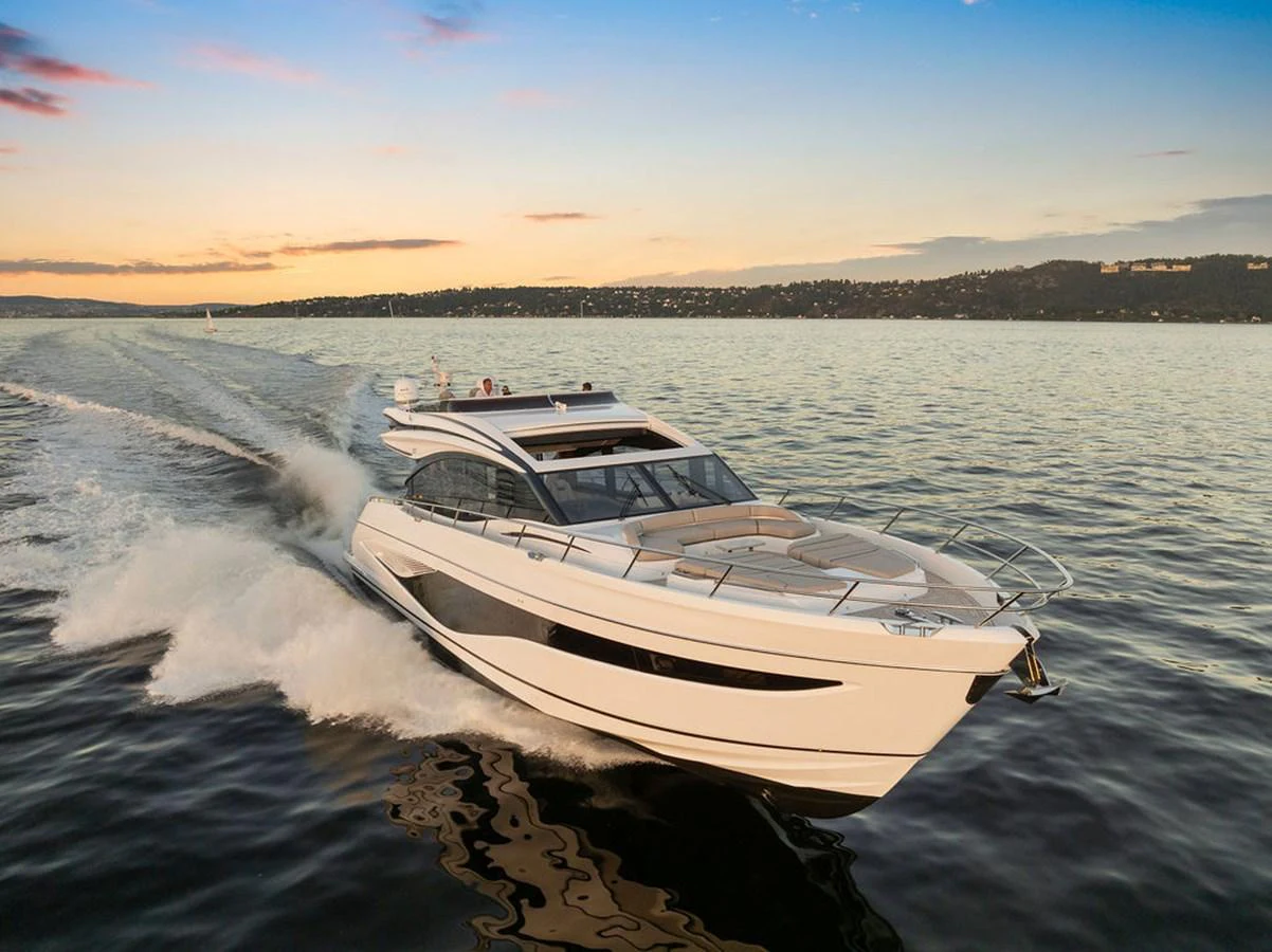 A sleek and modern yacht glides swiftly over the water at sunset. aboard PRINCESS S72 Yacht for Sale