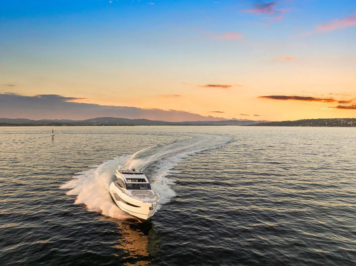 A sleek yacht cruises through calm waters at sunset, leaving a gentle wake behind. aboard PRINCESS S72 Yacht for Sale
