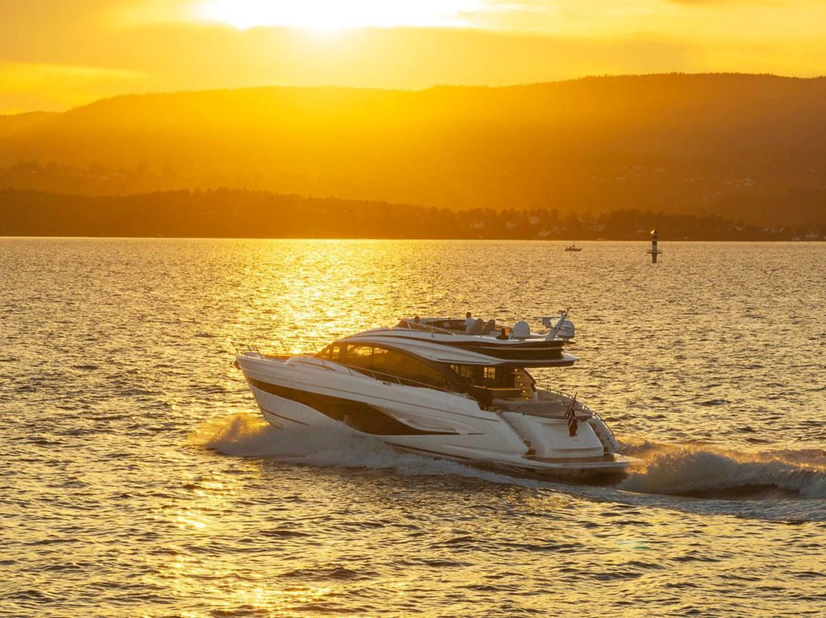 A sleek yacht cruises through golden waters at sunset, showcasing its elegant design. aboard PRINCESS S72 Yacht for Sale