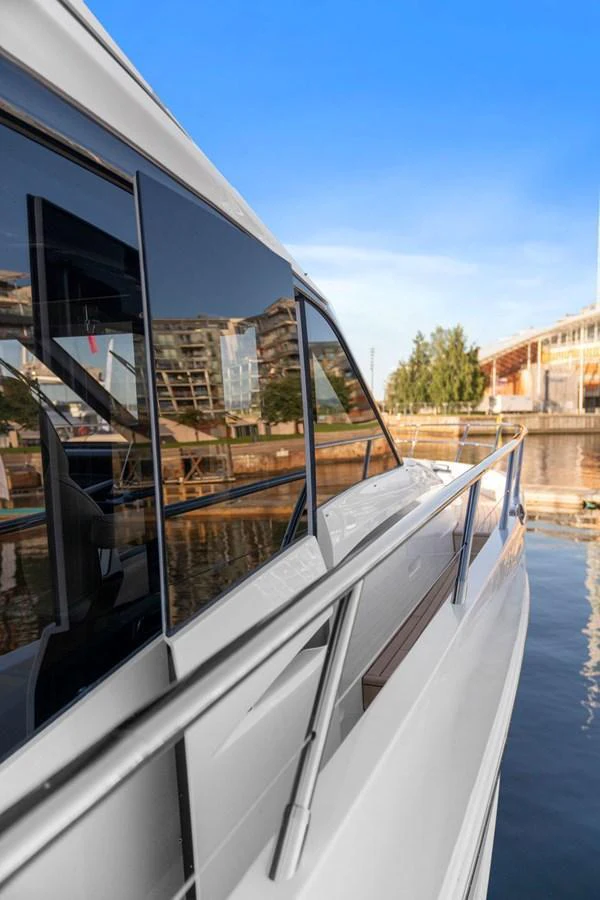 A sleek yacht is docked at a marina, reflecting the surrounding buildings on its windows. aboard PRINCESS S72 Yacht for Sale