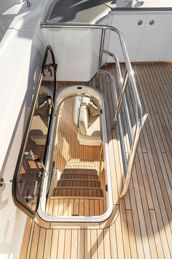 A well-crafted staircase with wooden steps leads down to the lower deck, framed by sleek stainless steel railings. aboard PRINCESS S72 Yacht for Sale