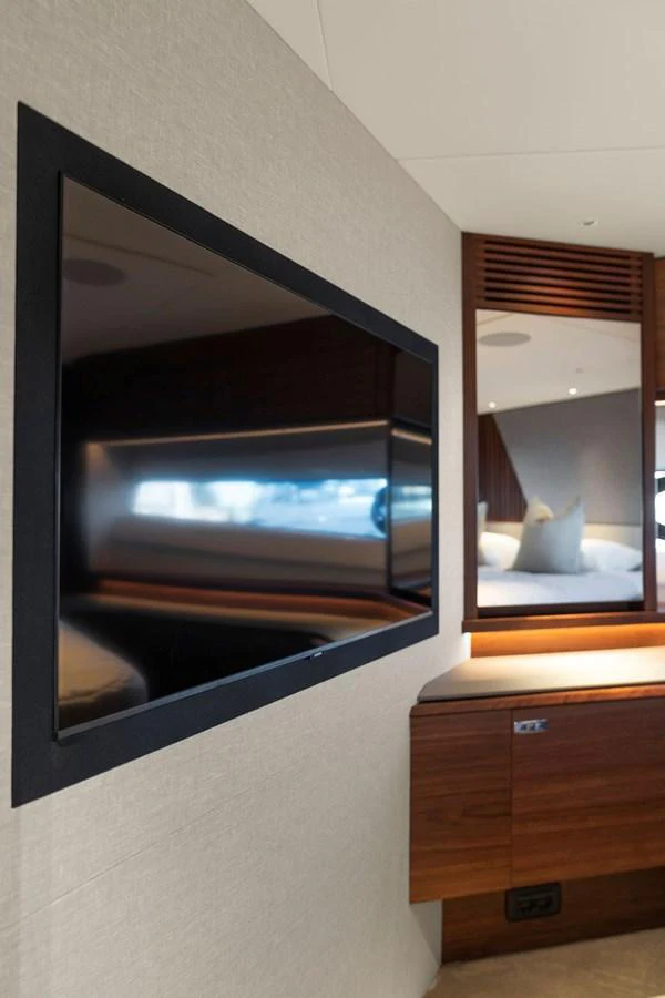 The stateroom features a wall-mounted flat-screen TV and a cozy bed with luxurious bedding. aboard PRINCESS S72 Yacht for Sale