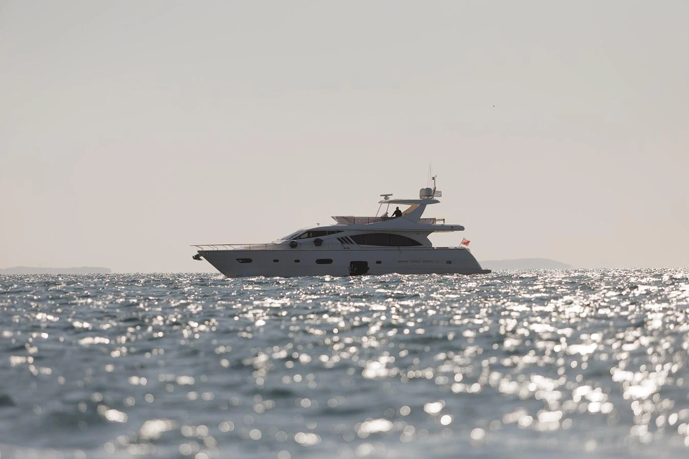 A sleek yacht glides gracefully on the shimmering water under a clear sky. aboard M/Y EM- II Yacht for Sale