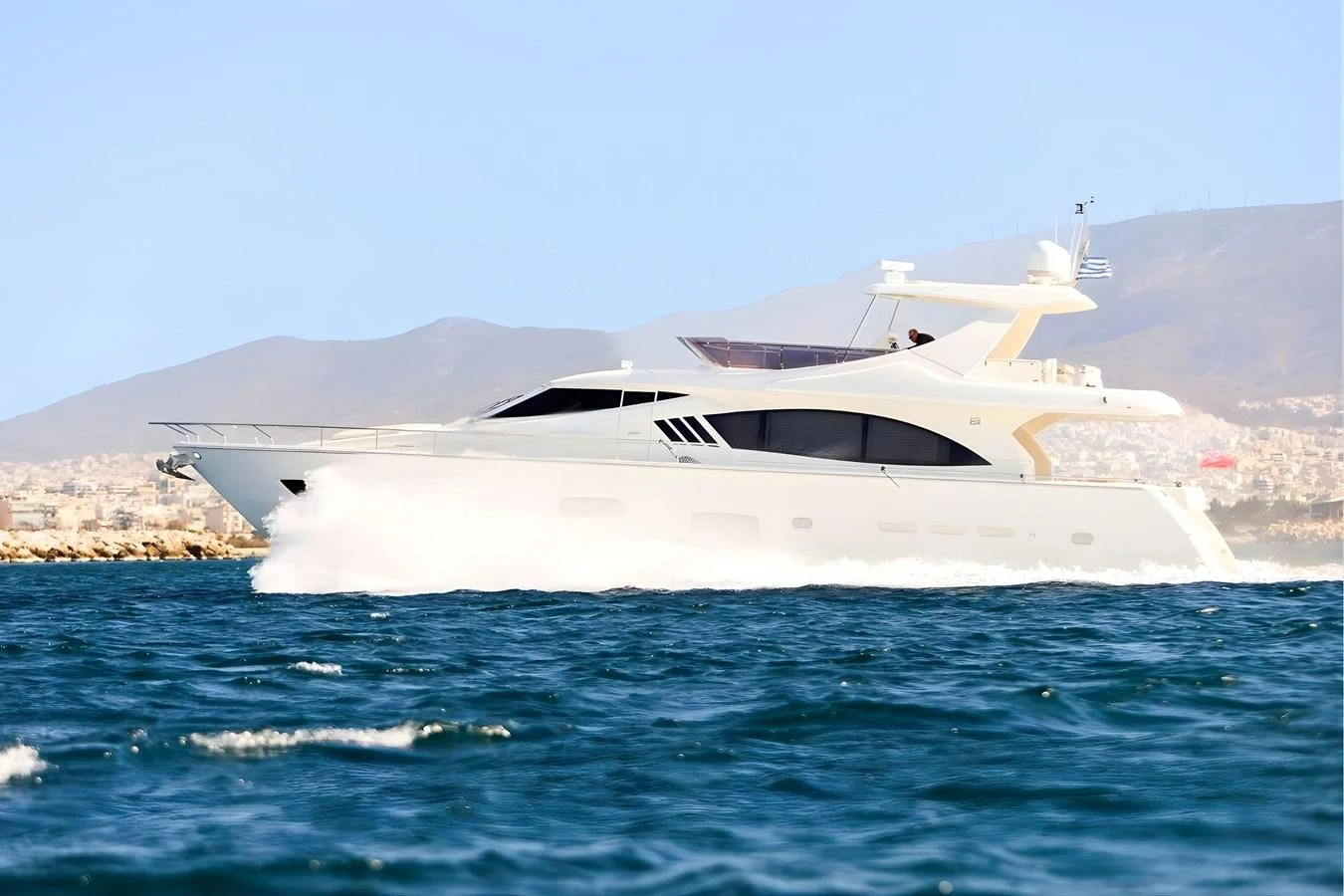 A sleek yacht cruises through the water with a scenic backdrop of mountains and coastline. aboard M/Y EM- II Yacht for Sale