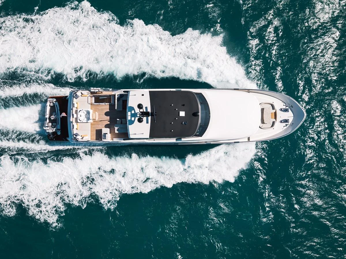 An aerial view of a sleek yacht cruising through the water, showcasing its elegant design and spacious deck areas. aboard LA LA LA Yacht for Sale