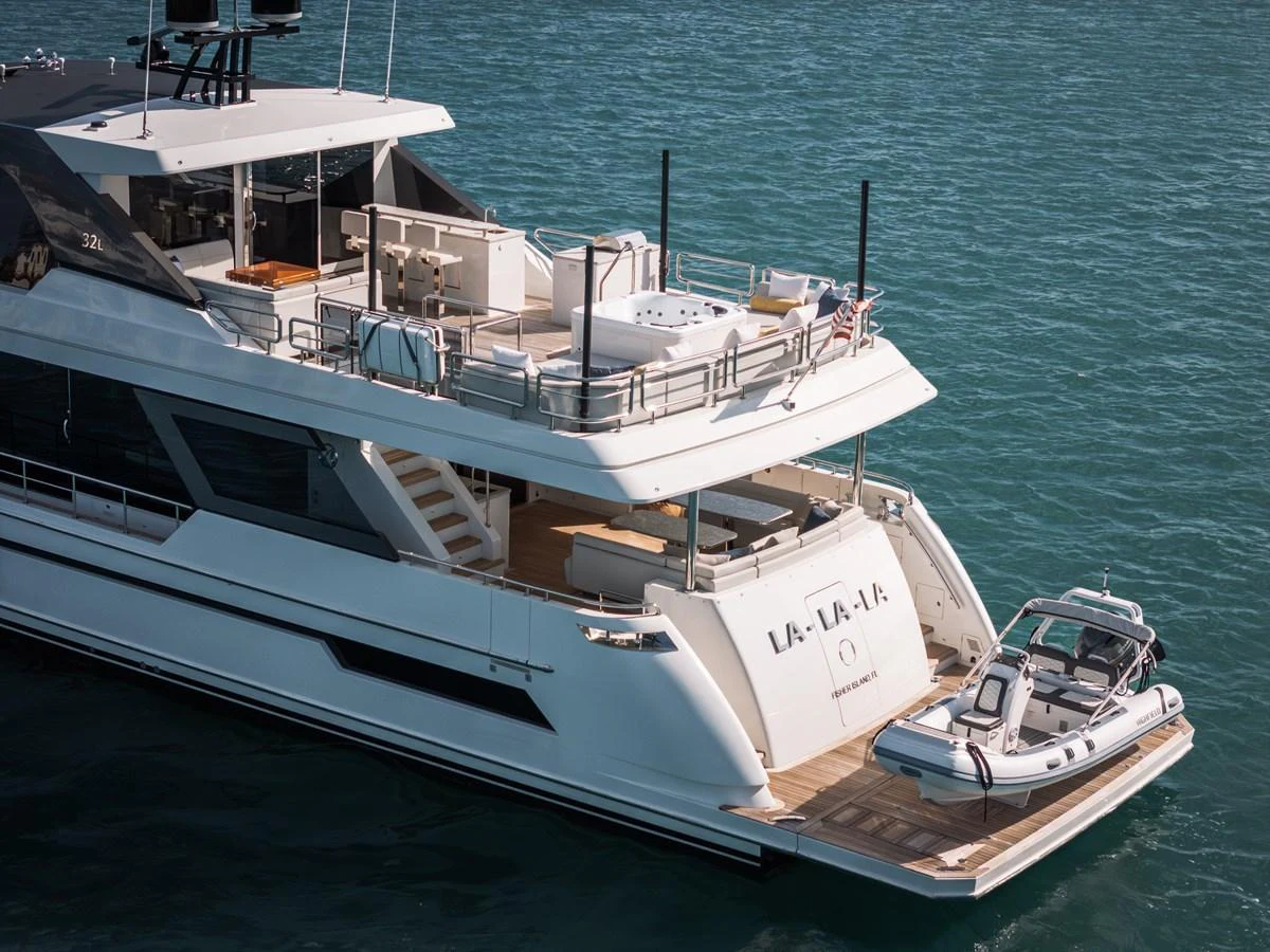 The yacht's aft deck features a spacious lounging area with a tender docked at the stern. aboard LA LA LA Yacht for Sale