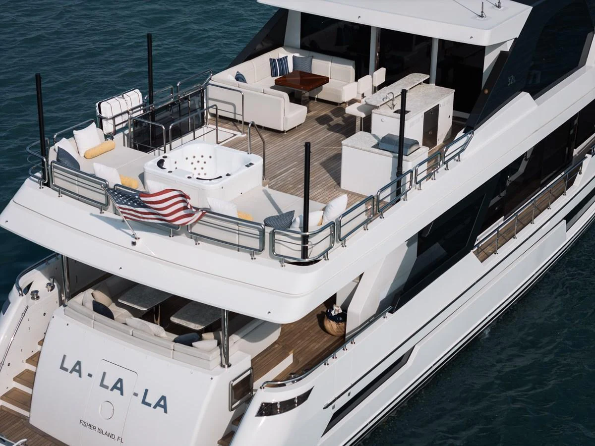 The yacht's aft deck features a luxurious lounging area with a hot tub and ample seating. aboard LA LA LA Yacht for Sale