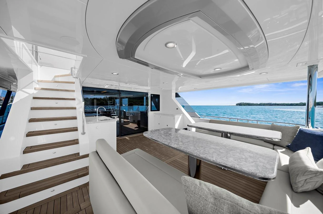 The aft deck features a spacious seating area with a sleek dining table, offering stunning views of the water. aboard LA LA LA Yacht for Sale