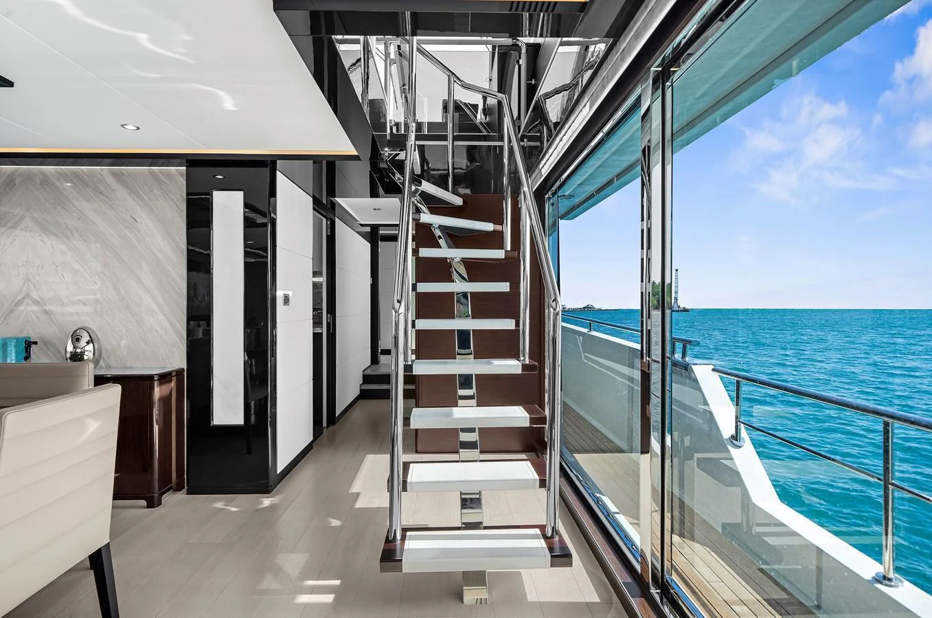 The main salon features a modern staircase with expansive ocean views through large windows. aboard LA LA LA Yacht for Sale