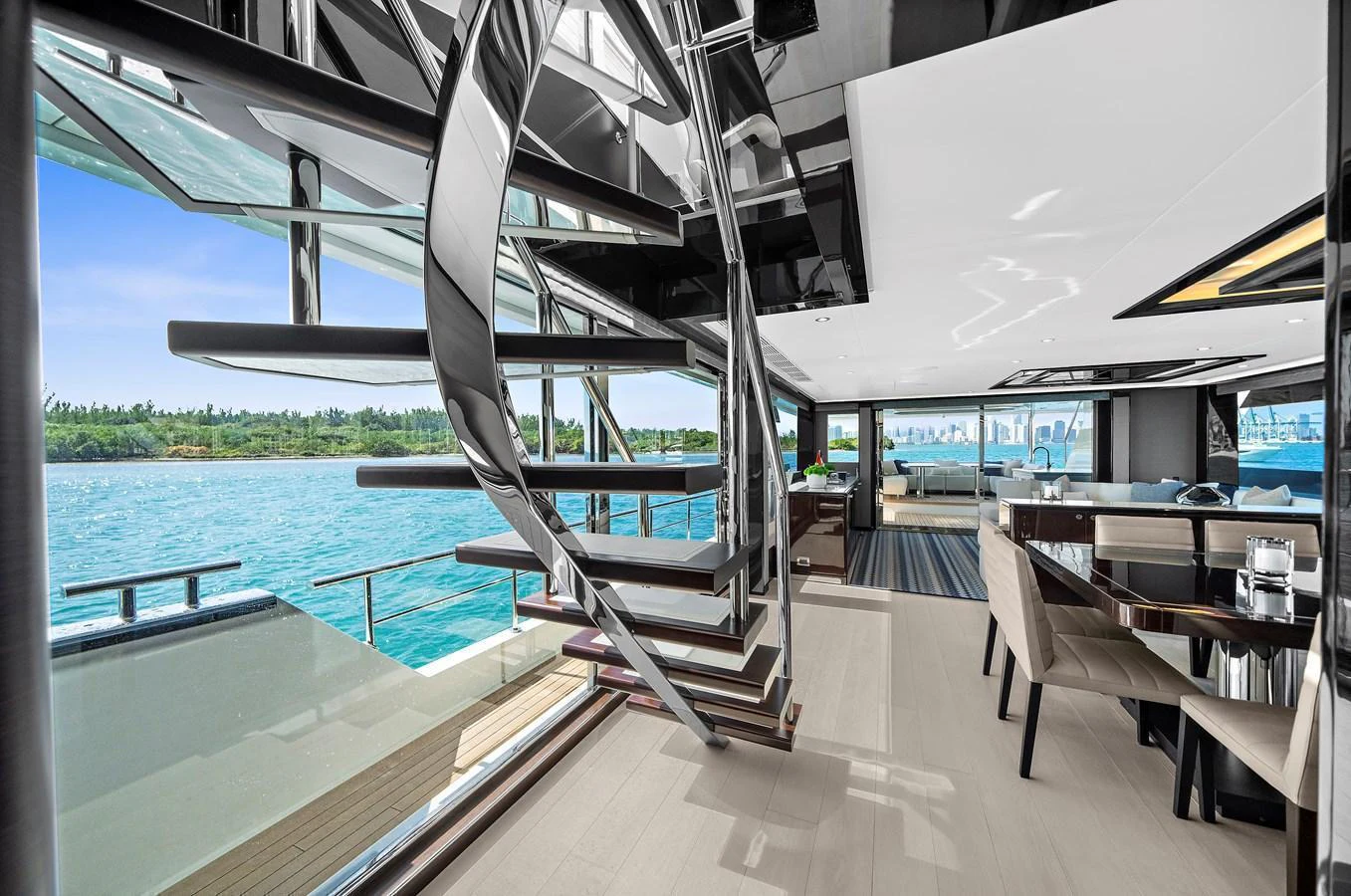 The main salon features a modern spiral staircase and expansive windows offering stunning ocean views. aboard LA LA LA Yacht for Sale