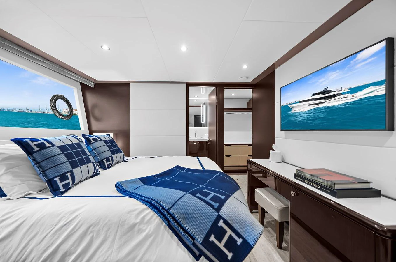 The stateroom features a luxurious bed with elegant bedding, a desk, and a large window offering a stunning sea view. aboard LA LA LA Yacht for Sale