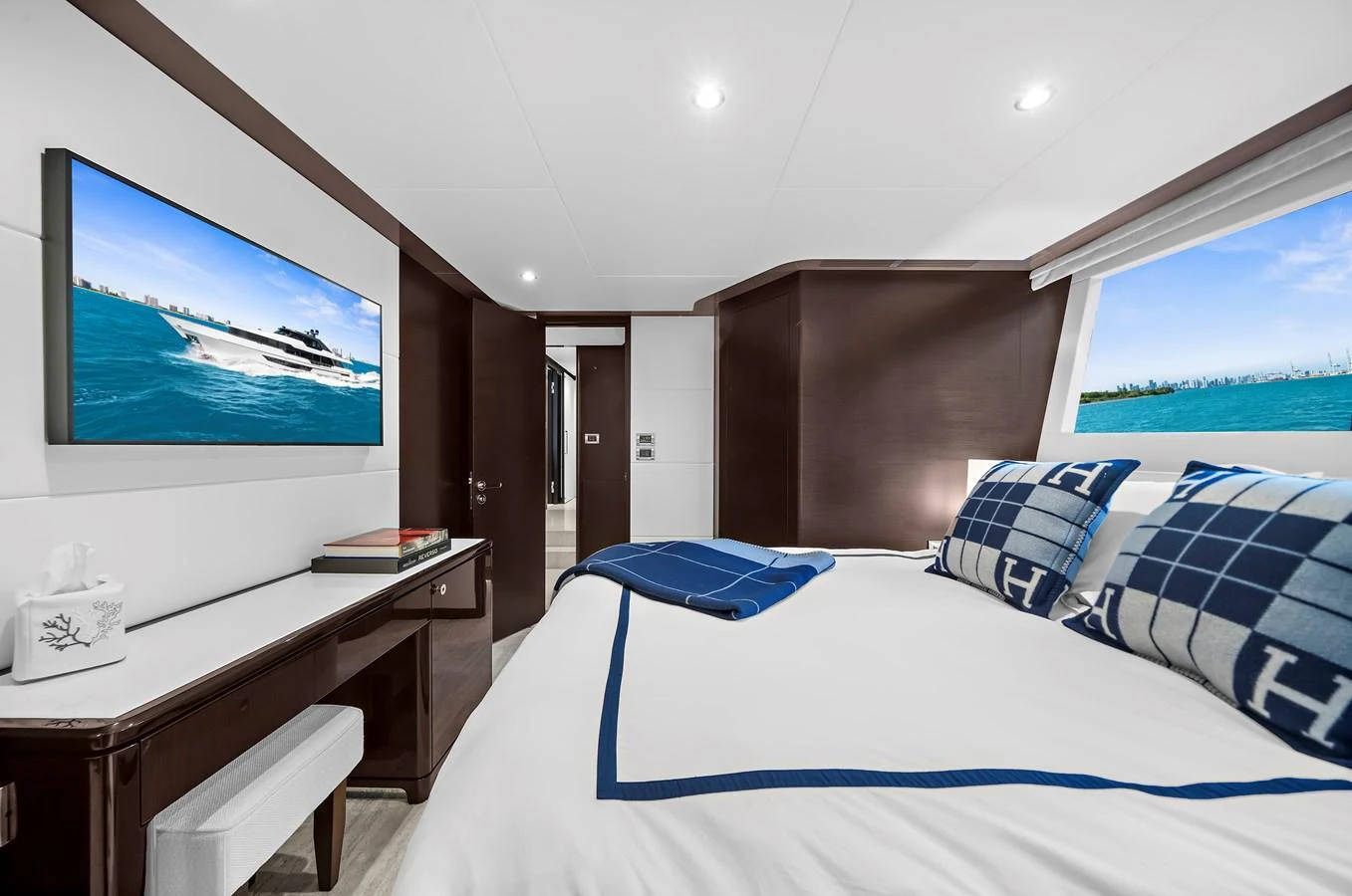 The stateroom features a luxurious bed with elegant bedding and a large window offering a scenic view. aboard LA LA LA Yacht for Sale