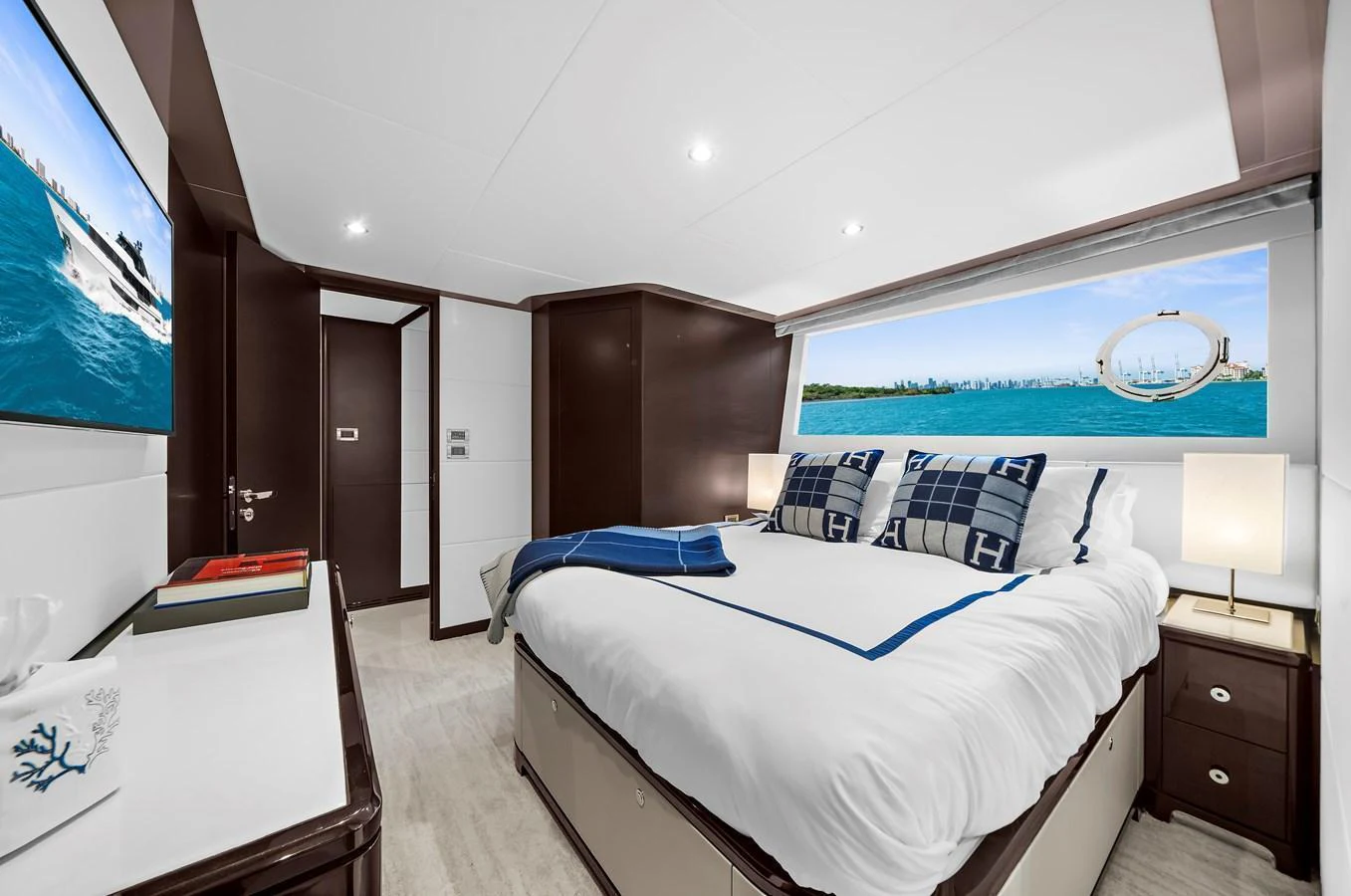 The stateroom features a luxurious bed with a scenic view through the large window. aboard LA LA LA Yacht for Sale