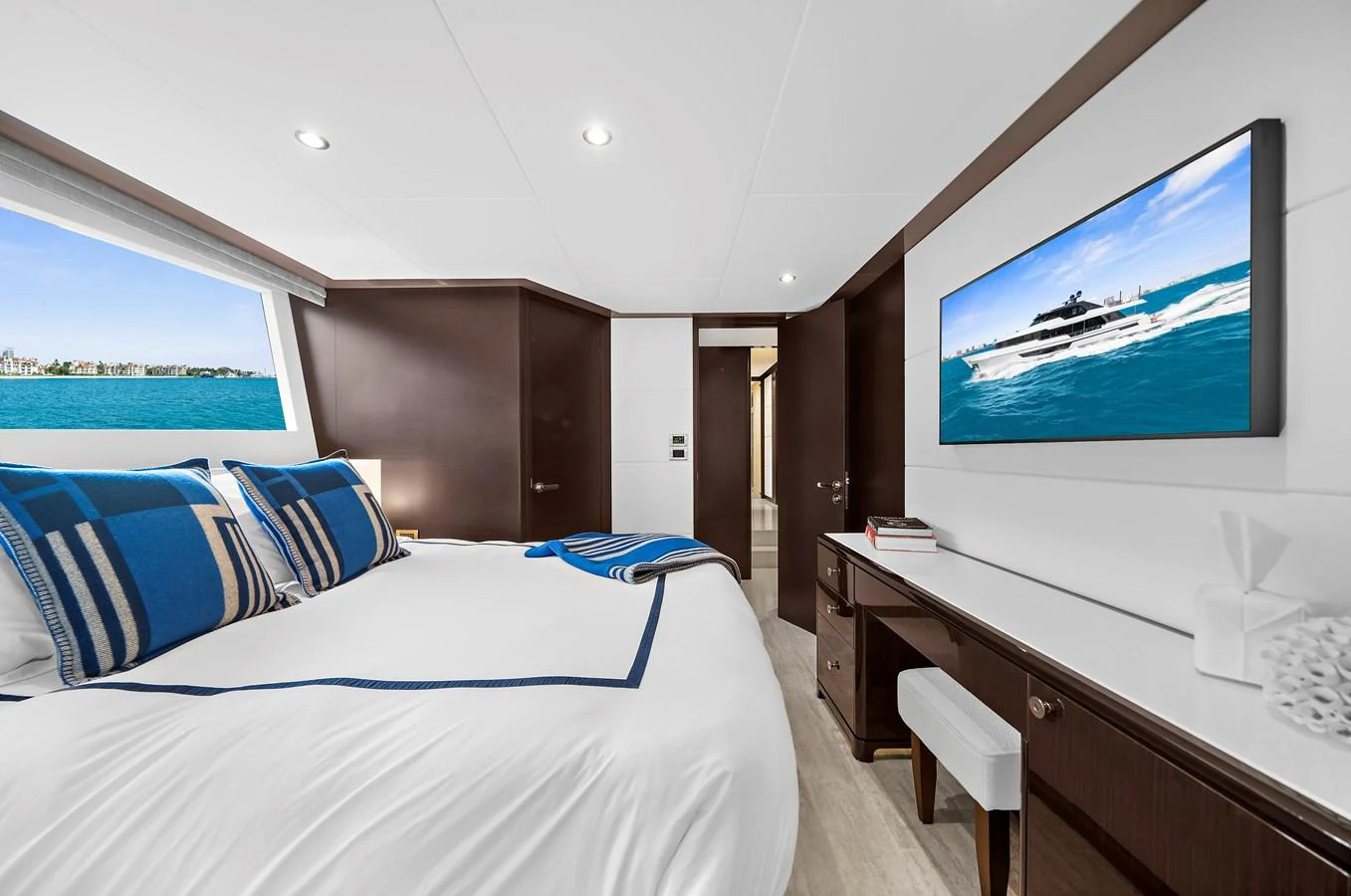 A luxurious stateroom featuring a large bed with blue accents and a view of the sea. aboard LA LA LA Yacht for Sale