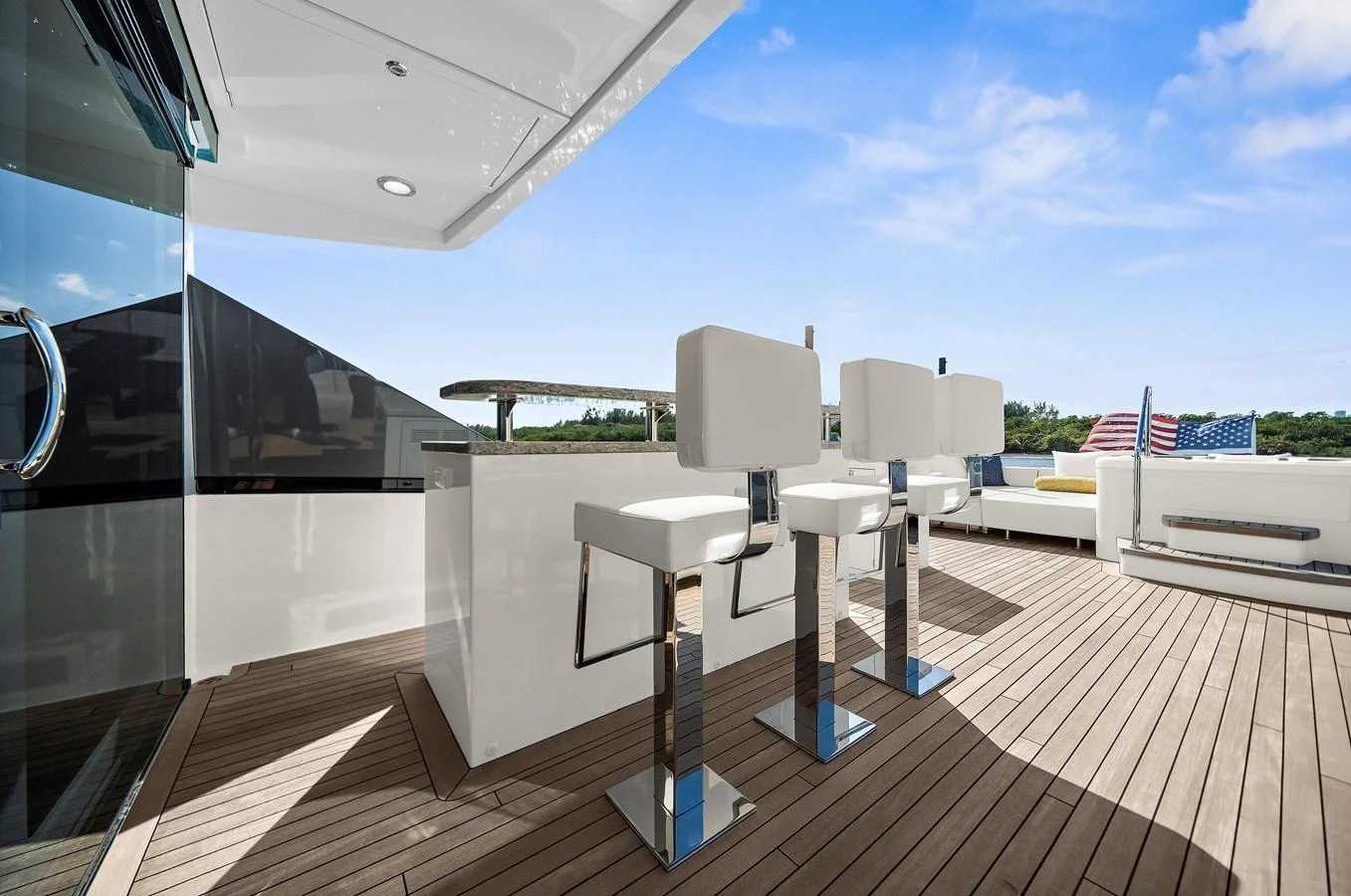 The aft deck features a sleek bar area with modern bar stools and ample seating, perfect for entertaining. aboard LA LA LA Yacht for Sale