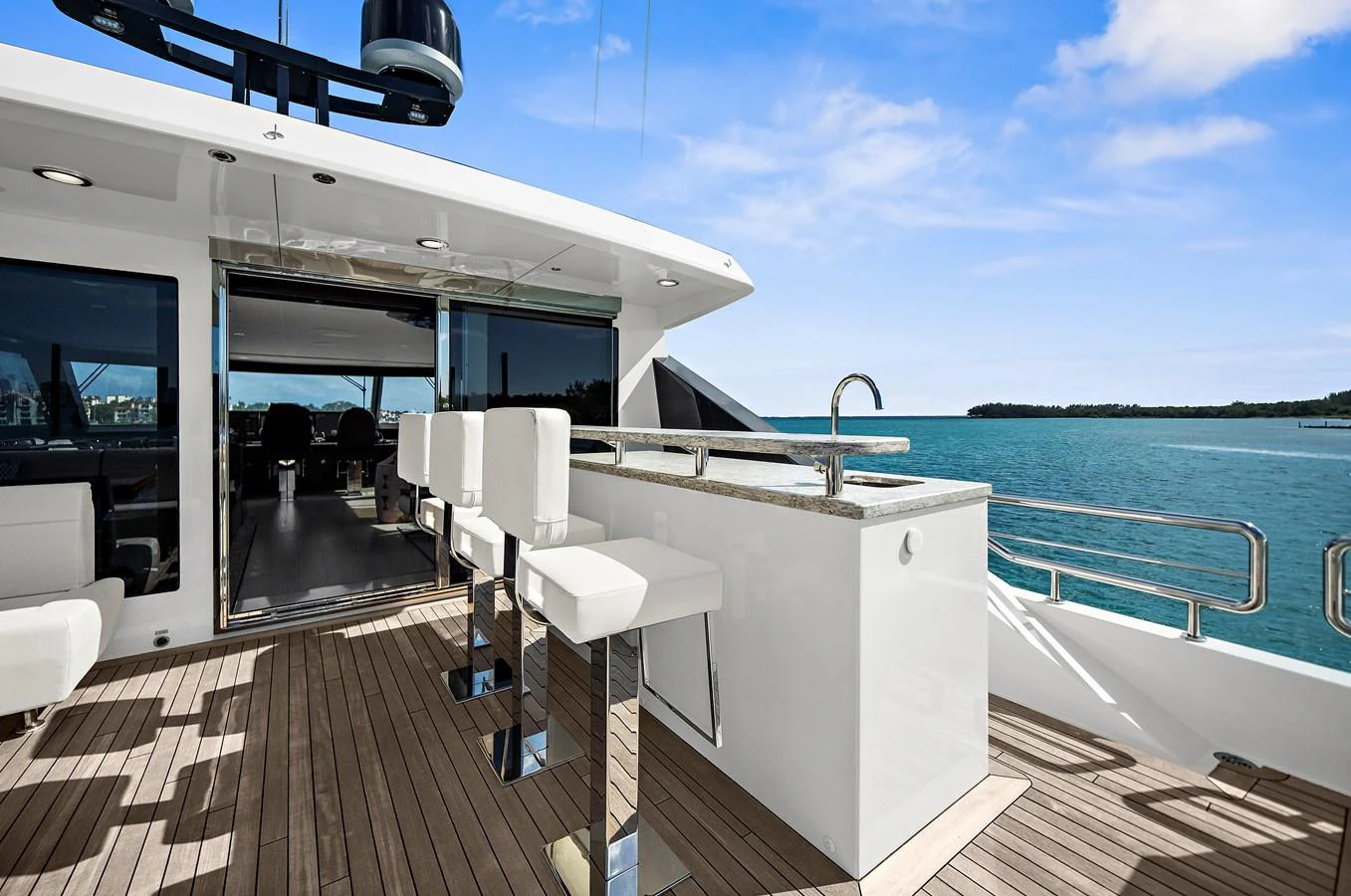 The flybridge features a sleek bar area with modern stools, offering stunning ocean views. aboard LA LA LA Yacht for Sale