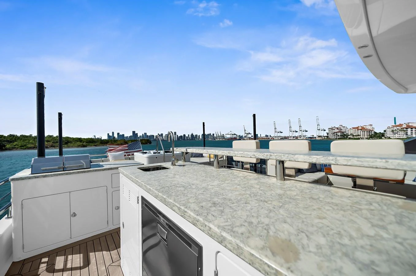 The yacht features a spacious outdoor galley with a stunning view of the city skyline. aboard LA LA LA Yacht for Sale