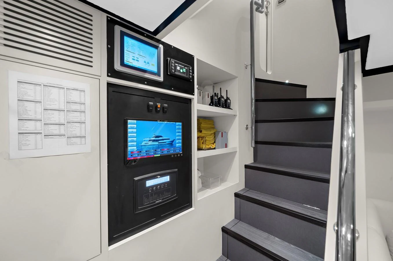 The image showcases a modern yacht's control room with advanced equipment and a staircase leading to another level. aboard LA LA LA Yacht for Sale