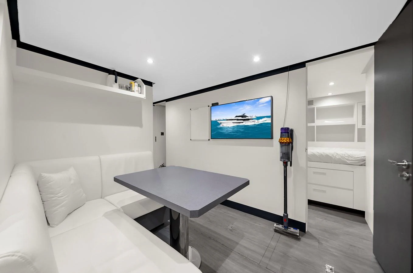A modern and cozy dining area with a wall-mounted TV and a sleek table. aboard LA LA LA Yacht for Sale
