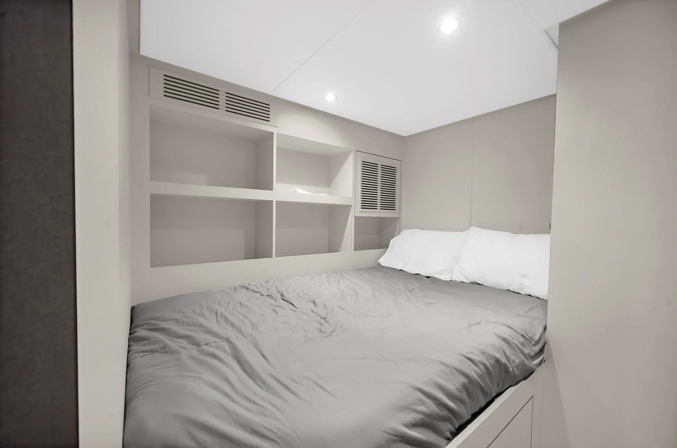 A cozy stateroom with a neatly made bed and built-in shelving. aboard LA LA LA Yacht for Sale