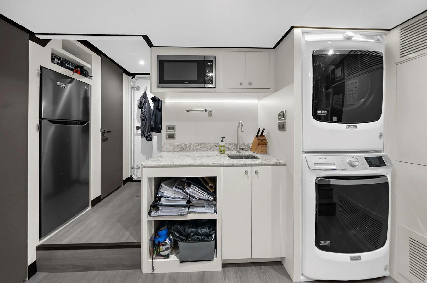 This image showcases a modern galley with a compact yet functional design, featuring a washer and dryer unit. aboard LA LA LA Yacht for Sale