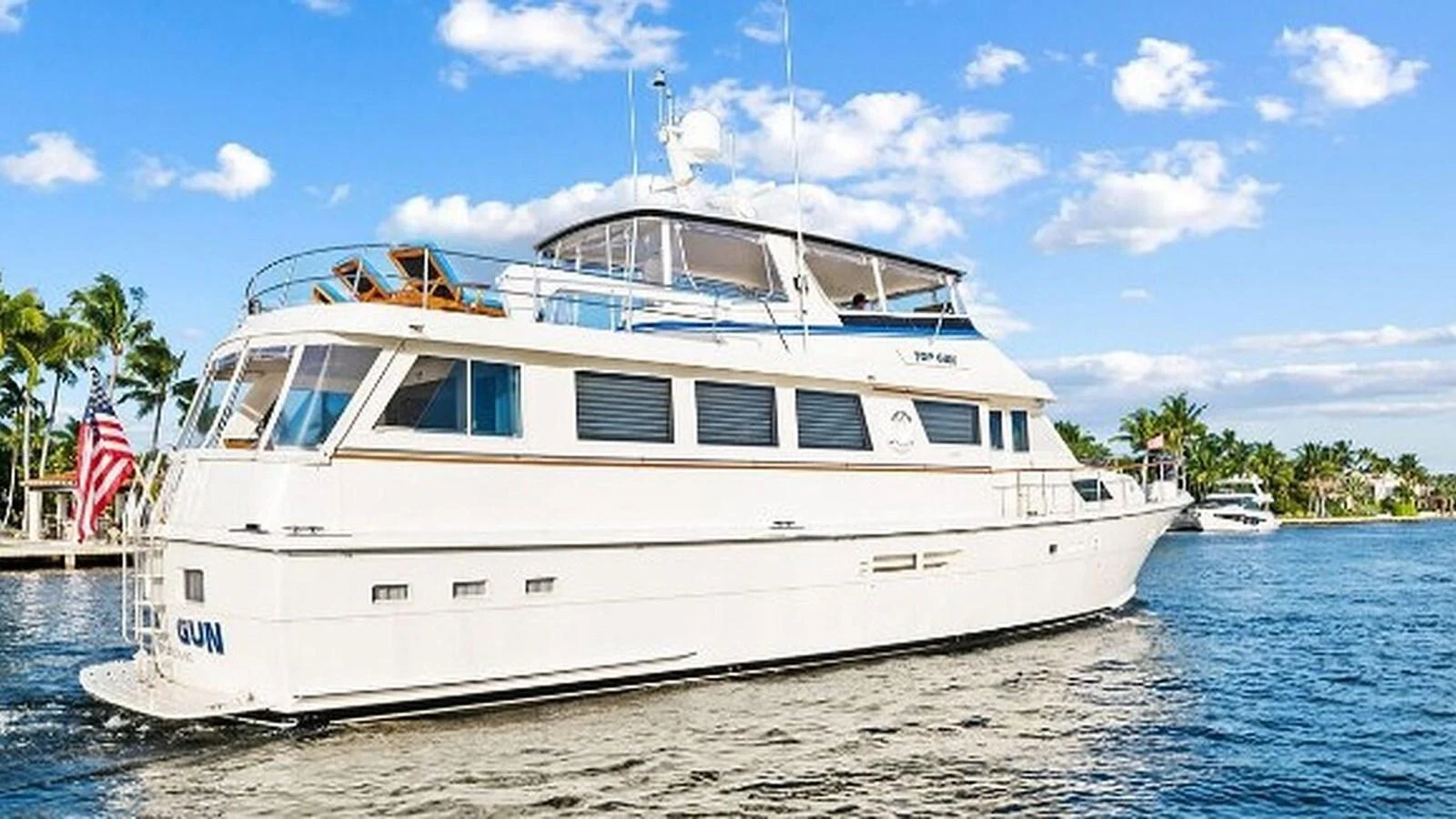 A luxurious yacht cruising on calm waters under a clear blue sky. aboard TOP GUN Yacht for Sale