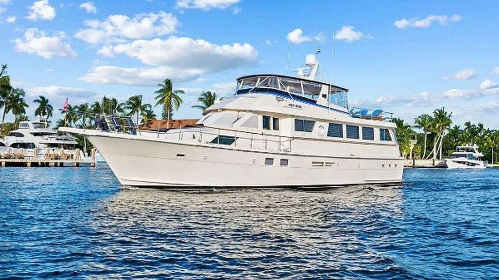 A luxurious yacht cruises gracefully on calm waters under a clear blue sky. aboard TOP GUN Yacht for Sale
