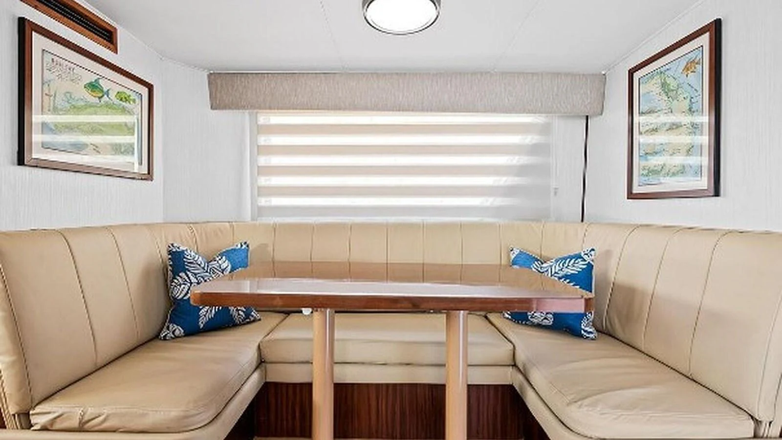 The yacht's dining area features a cozy, upholstered seating arrangement with a wooden table and nautical-themed decor. aboard TOP GUN Yacht for Sale