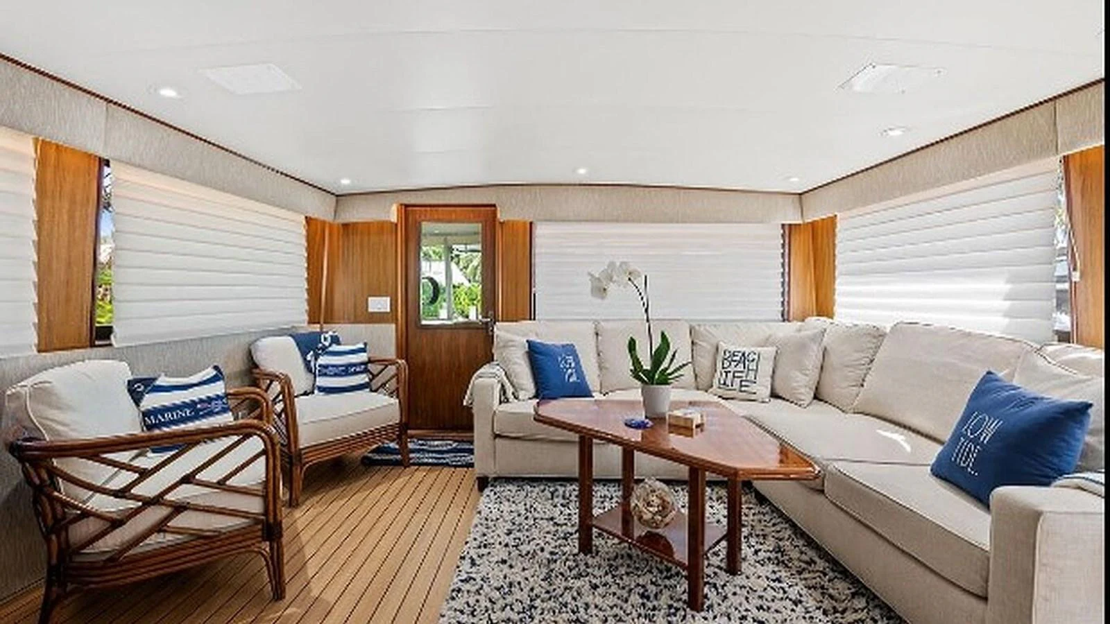 The salon features comfortable seating with a mix of sofas and armchairs, complemented by a wooden coffee table and nautical-themed decor. aboard TOP GUN Yacht for Sale
