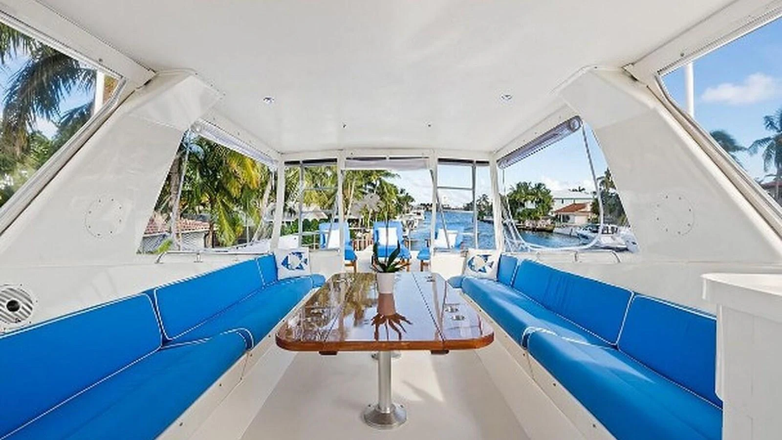 The salon features a spacious seating area with vibrant blue cushions and a polished wooden table, offering a comfortable and stylish space to relax. aboard TOP GUN Yacht for Sale