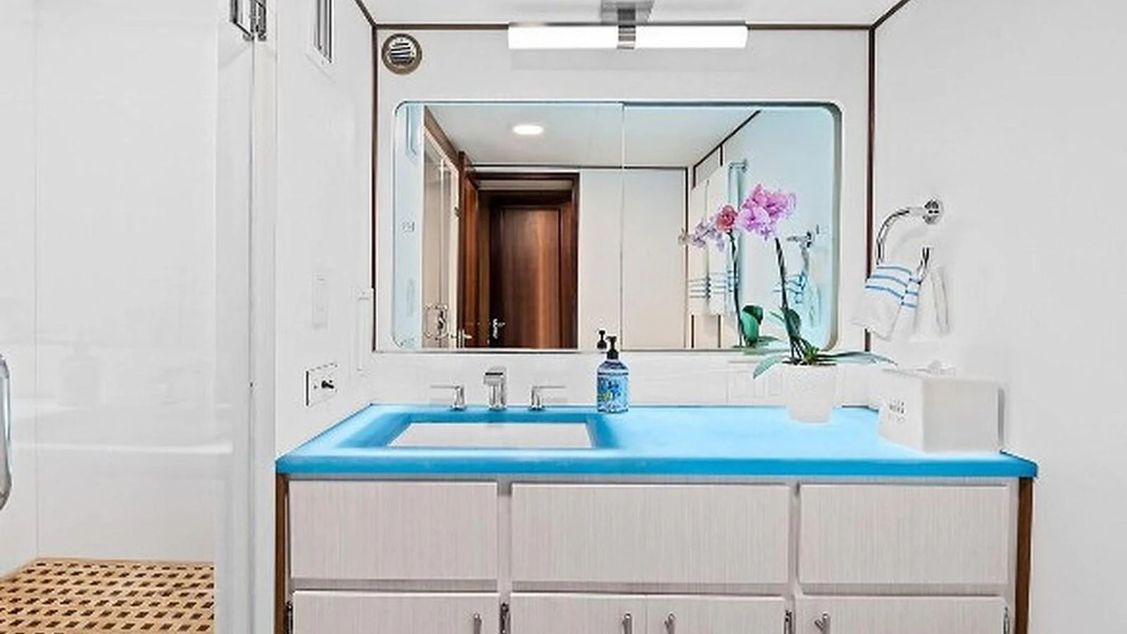 A modern yacht bathroom featuring a sleek sink and a vibrant blue countertop. aboard TOP GUN Yacht for Sale