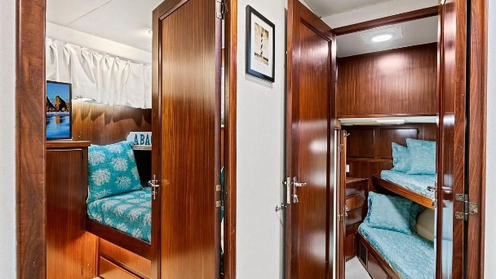 The image showcases a cozy cabin area with wooden finishes and comfortable bedding. aboard TOP GUN Yacht for Sale