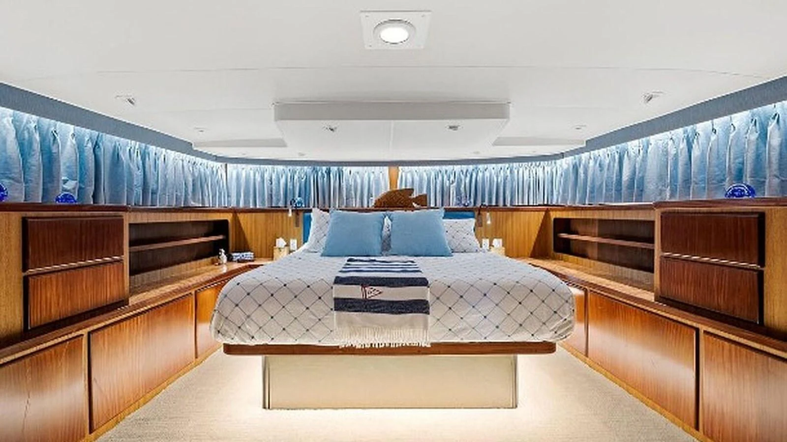 The master stateroom features a spacious bed with elegant wooden cabinetry and ambient lighting. aboard TOP GUN Yacht for Sale