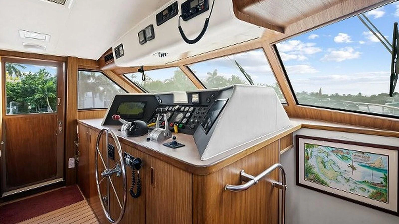 The helm station features a classic wooden design with modern navigation equipment and panoramic windows offering a clear view. aboard TOP GUN Yacht for Sale