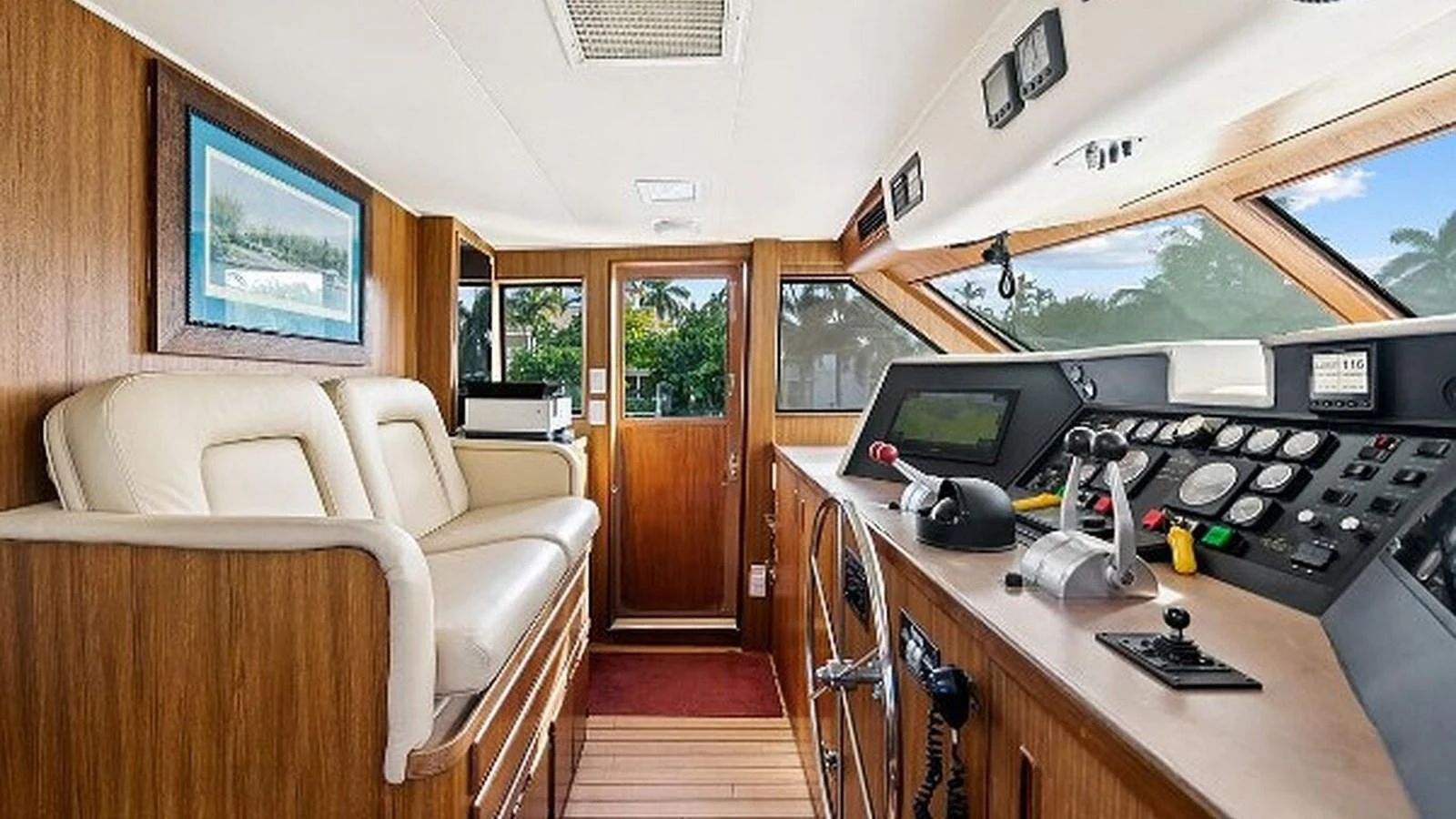 The helm station features a blend of modern controls and classic wooden finishes, offering a comfortable and stylish navigation area. aboard TOP GUN Yacht for Sale