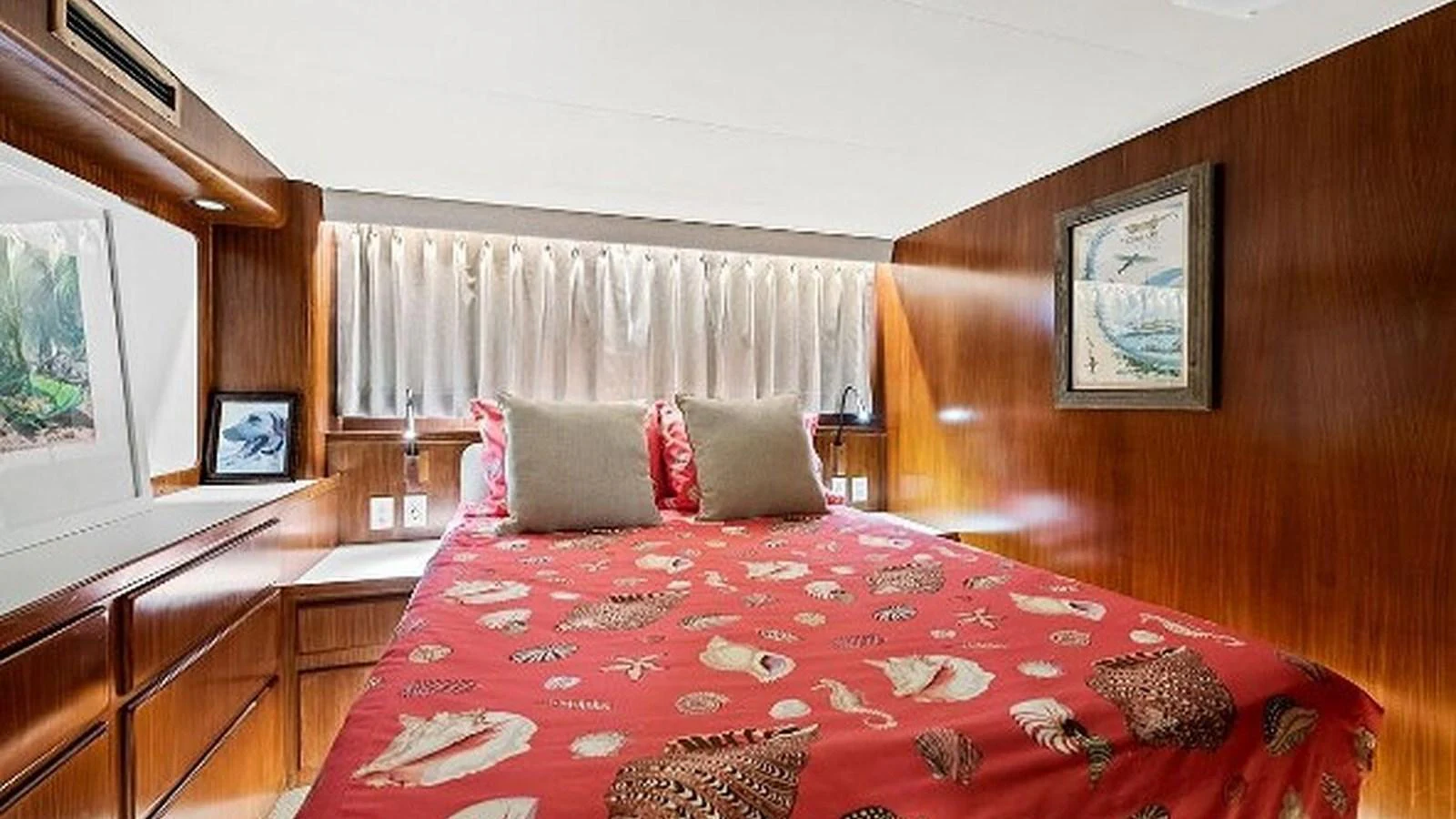 A cozy stateroom with a vibrant red bedspread and wooden paneling. aboard TOP GUN Yacht for Sale