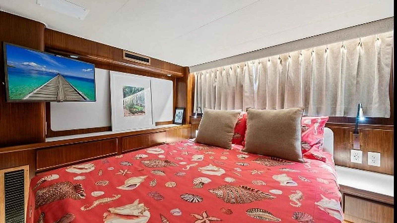 A cozy stateroom featuring a large bed with vibrant bedding and a wall-mounted TV. aboard TOP GUN Yacht for Sale
