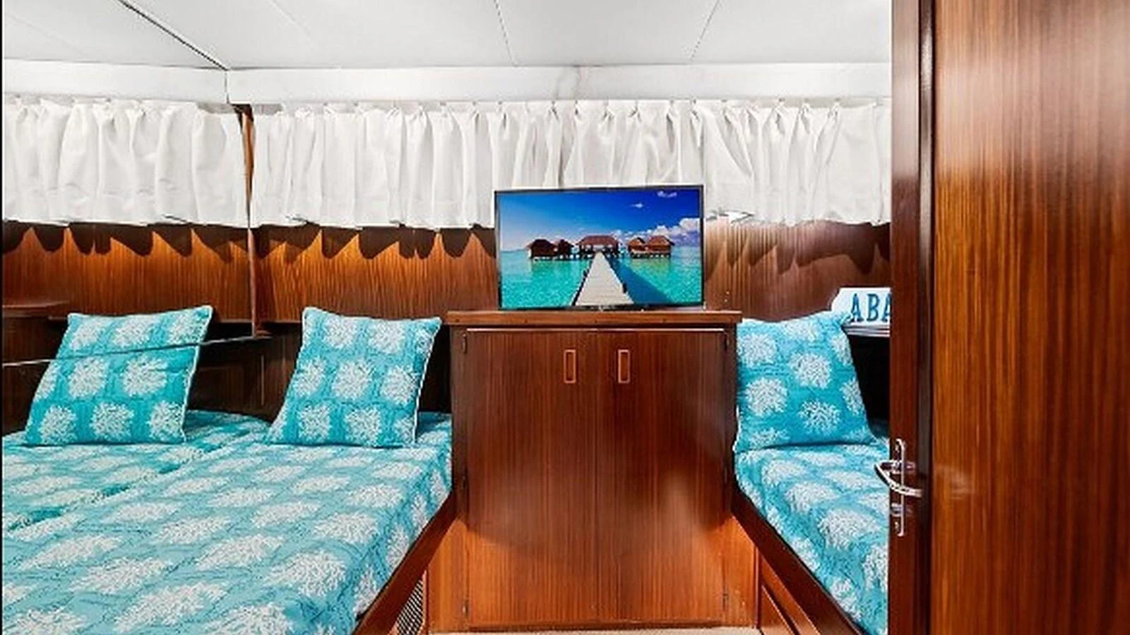 The stateroom features twin beds with vibrant bedding and a flat-screen TV for entertainment. aboard TOP GUN Yacht for Sale