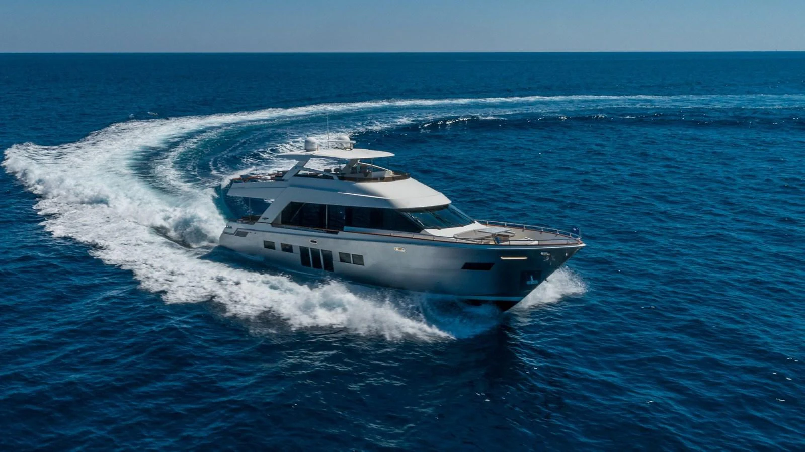 A sleek yacht cruises through the open sea, leaving a trail of white wake behind. aboard WHISTLE Yacht for Sale