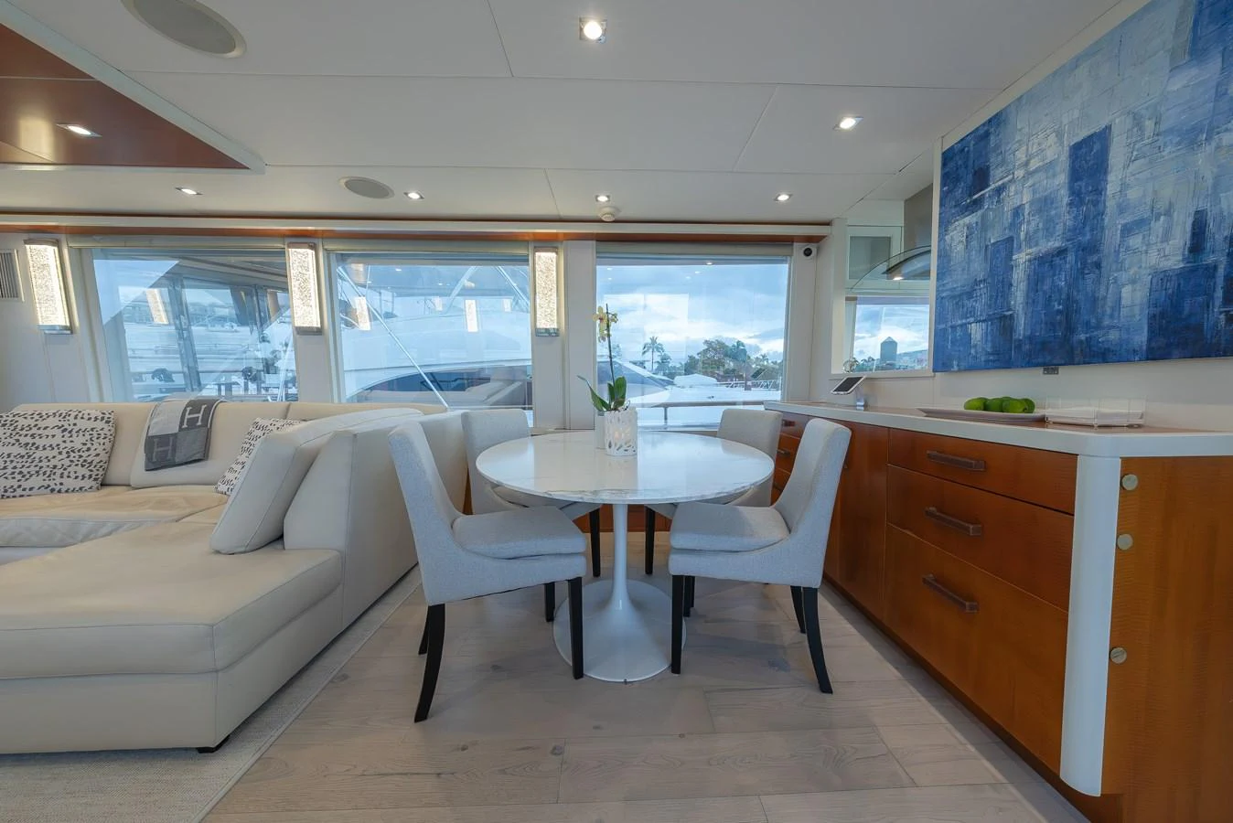 The salon features a cozy dining area with a round table and comfortable seating, complemented by large windows and modern decor. aboard WHISTLE Yacht for Sale