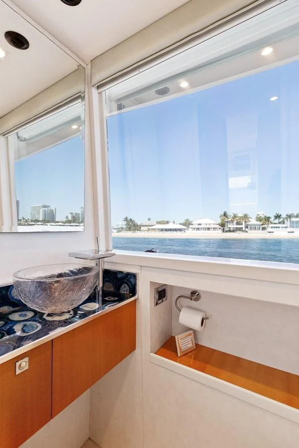 A stylish yacht bathroom with a modern glass sink and a scenic view through the window. aboard WHISTLE Yacht for Sale