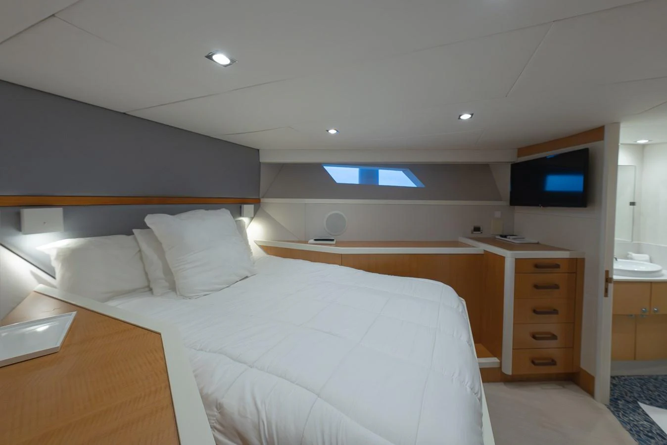 The stateroom features a cozy bed with modern furnishings and ample lighting. aboard WHISTLE Yacht for Sale