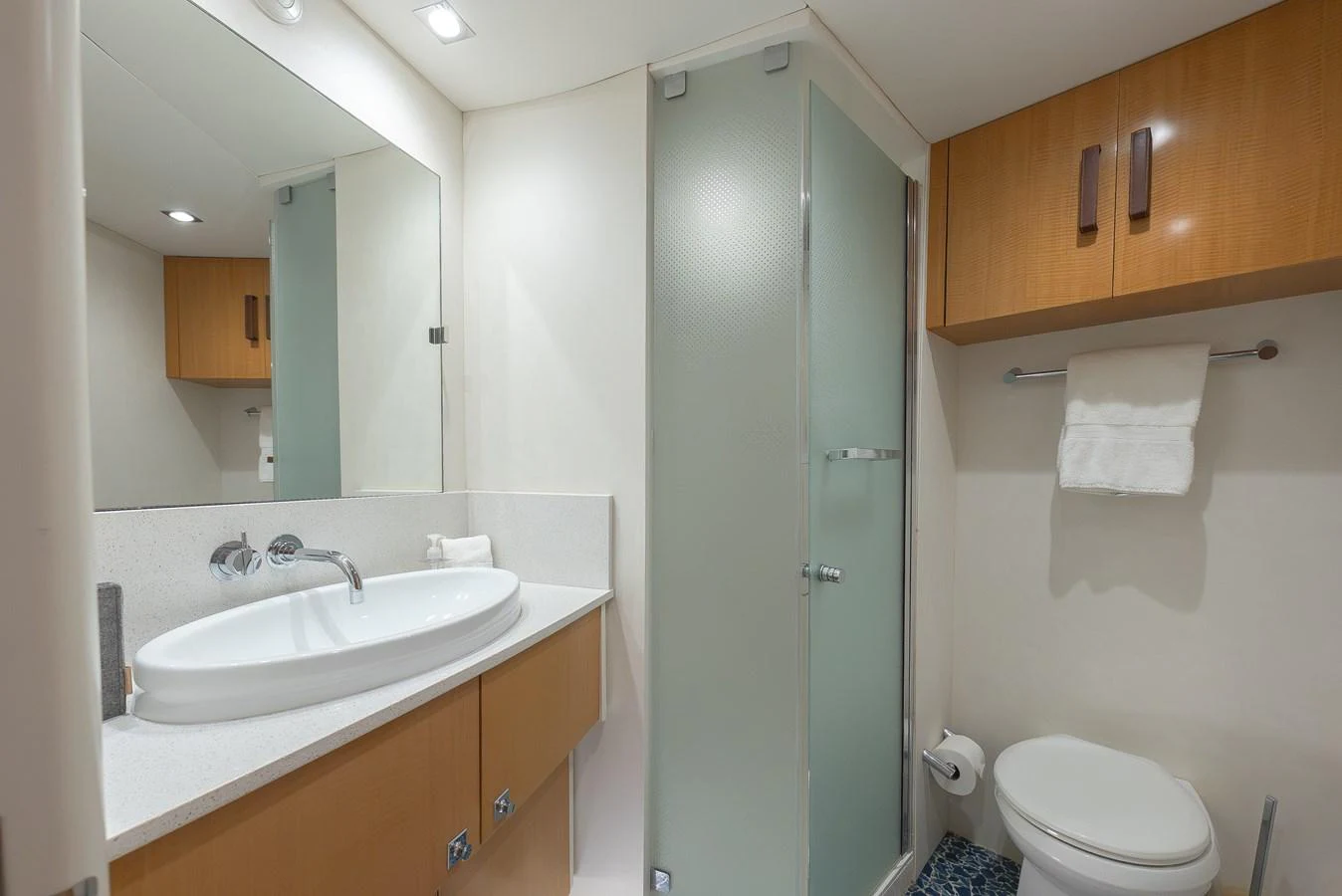 A modern yacht bathroom featuring a sleek sink, a glass-enclosed shower, and wooden cabinetry. aboard WHISTLE Yacht for Sale