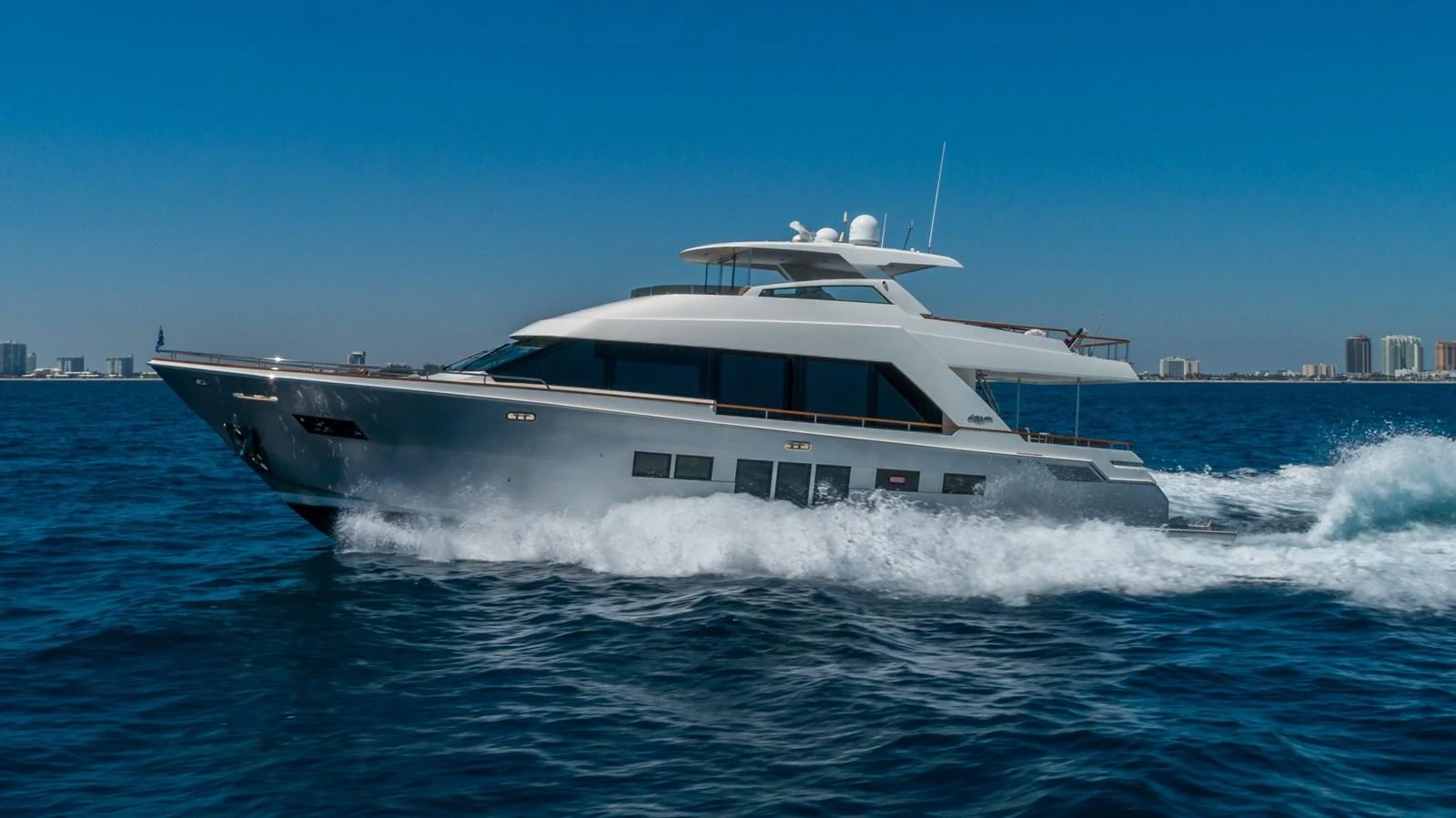 A sleek yacht cruises swiftly through the open water under a clear blue sky. aboard WHISTLE Yacht for Sale