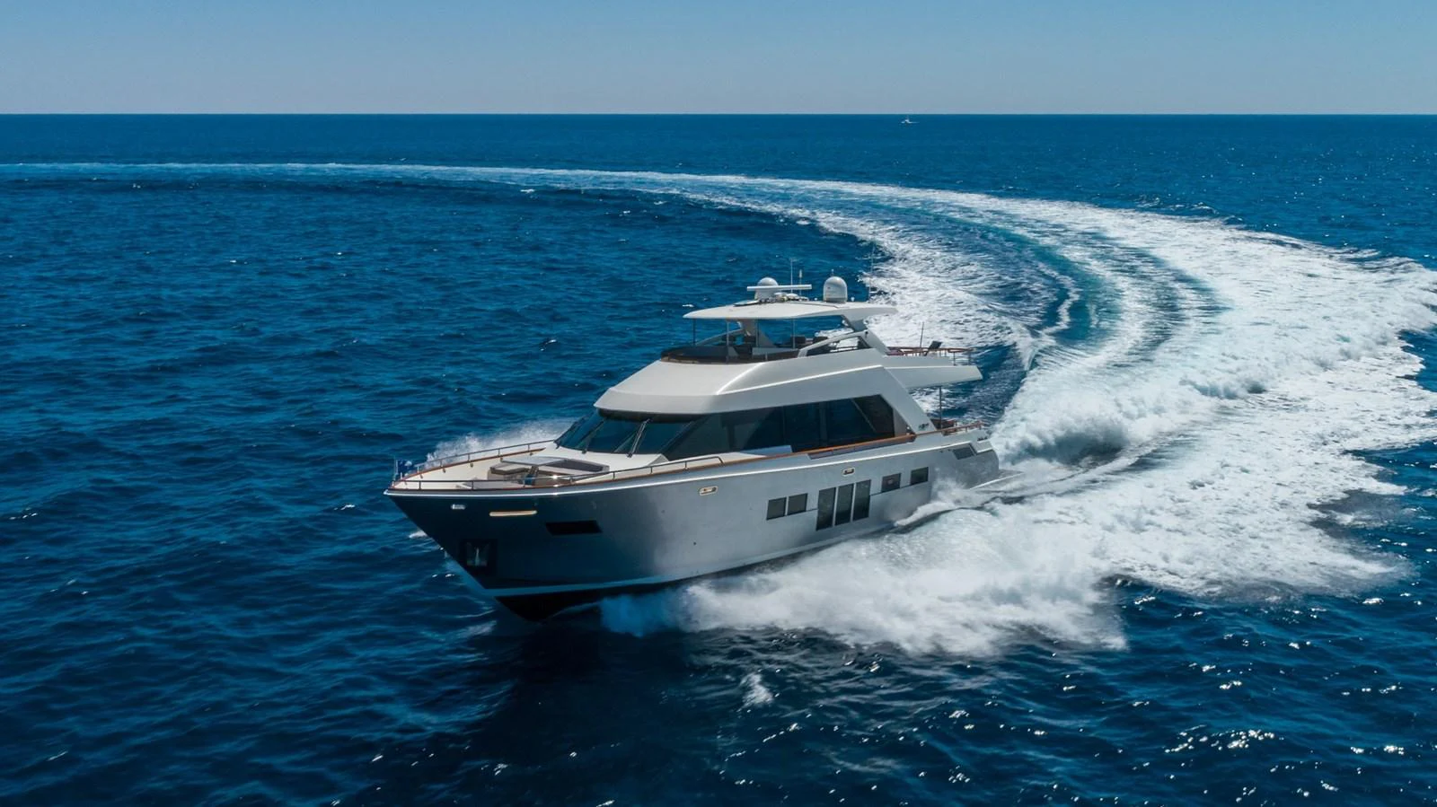 A sleek yacht glides swiftly through the open sea, leaving a trail of white wake behind. aboard WHISTLE Yacht for Sale